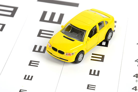 Ein Spielzeugauto auf einer Augentafel symbolisiert die Bedeutung einer Augenuntersuchung für das Autofahren.